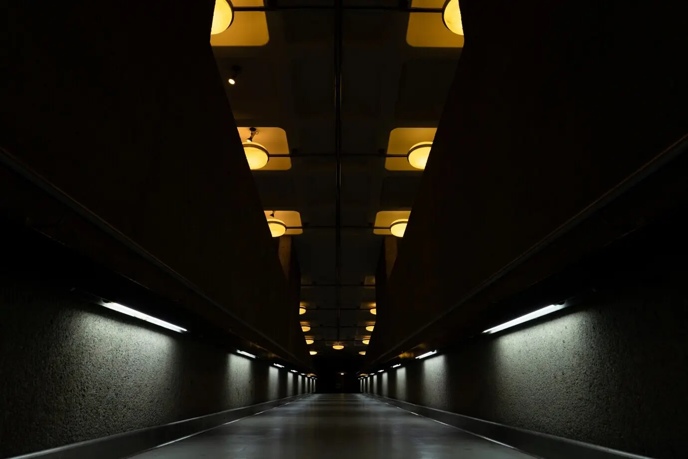 A dark tunnel with ceiling lamps switched on
