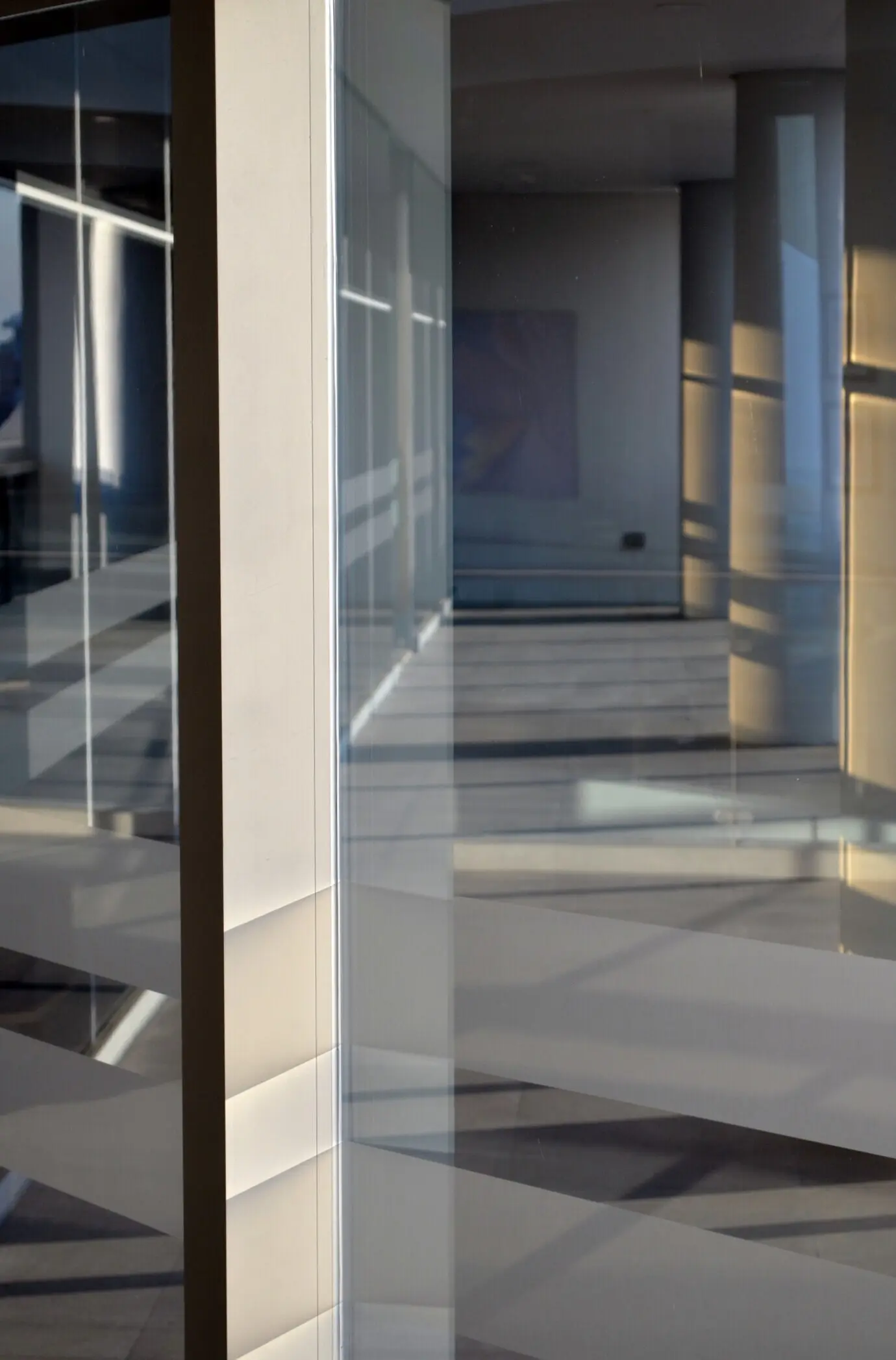 The interior of a contemporary building with glass windows and a white ambiance.