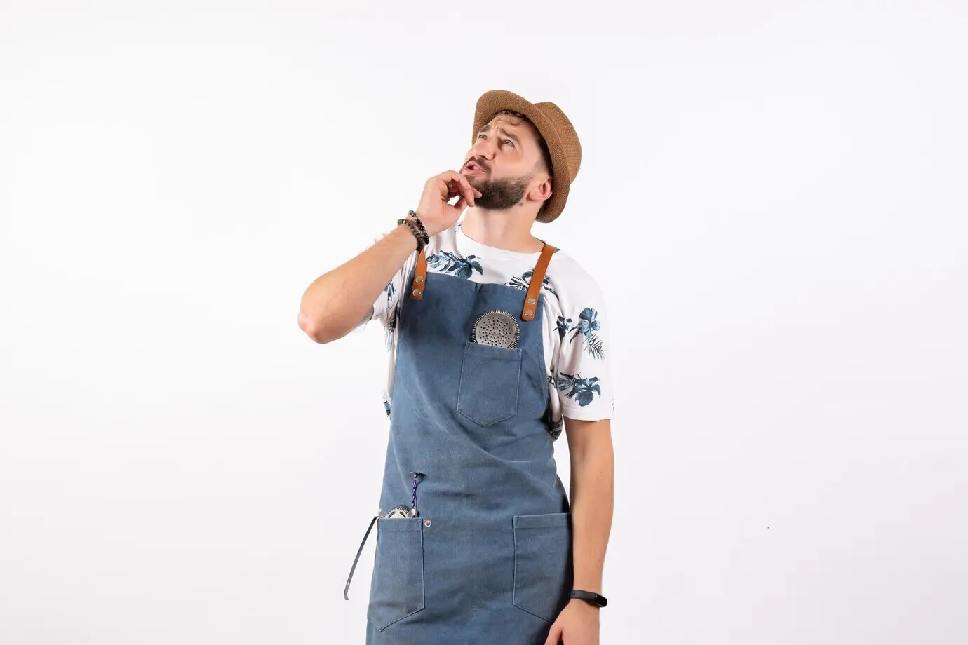 Front view of a male bartender gazing up at the ceiling, thinking, against a white wall; alcohol, job, club, night, drink, bar, nut.